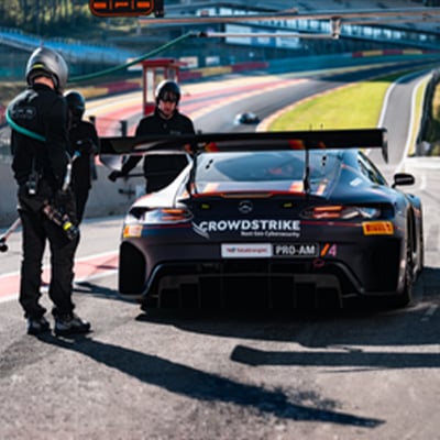 Race team members beside a race car in pit lane, preparing for or completing a stop