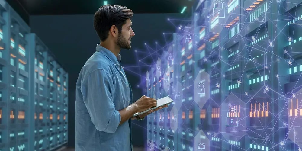 Person holding a tablet while standing in a server room with illuminated racks and digital security icons overlayed, representing enterprise storage and data protection.