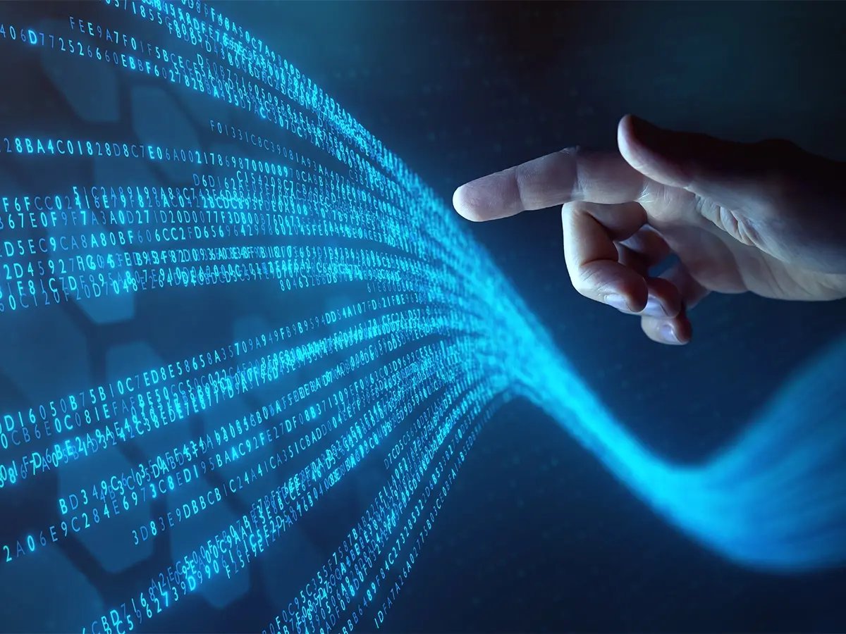 Hand pointing at flowing streams of glowing blue binary code on a dark digital background, representing data virtualization.