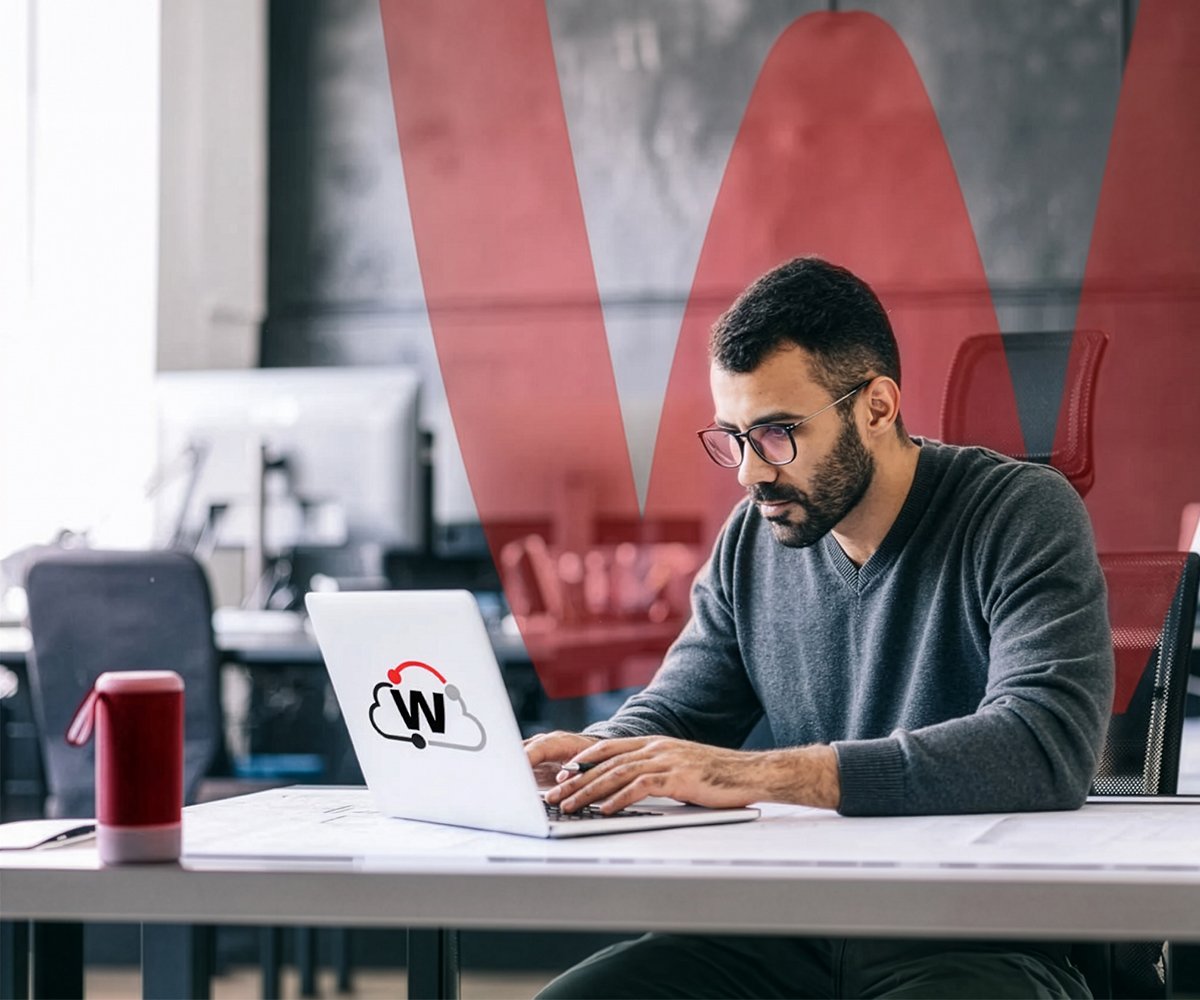 Person working on a laptop at a desk with a red overlay graphic and a cloud security icon on the screen