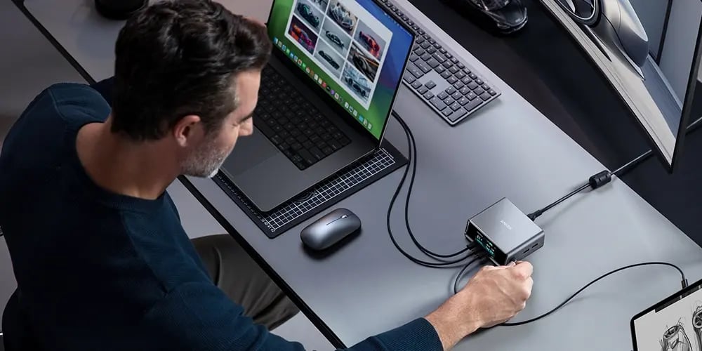 Person connecting a laptop to a docking station on a desk.