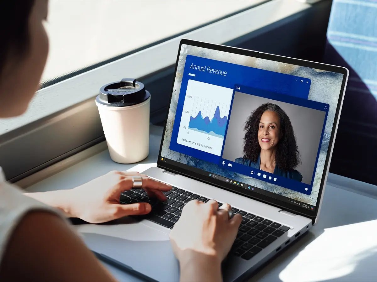 Person working on a laptop showing a video call and revenue charts.