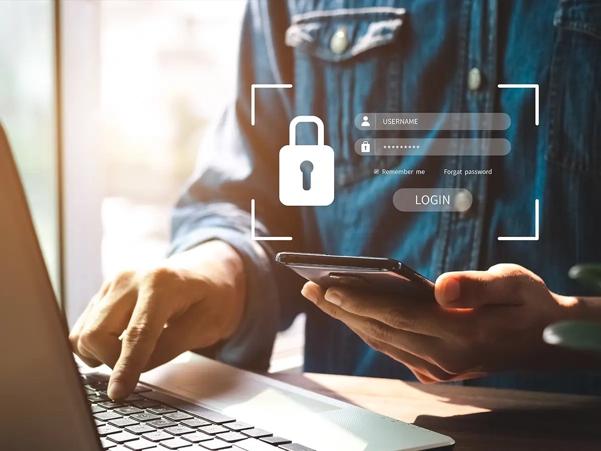 Person using a smartphone and laptop with a secure login interface overlay.