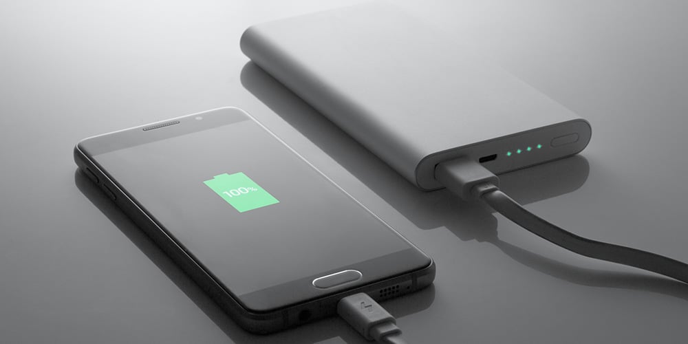 Smartphone connected to a power bank showing a full battery icon.
