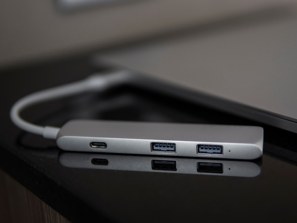 USB‑C hub with USB ports and a cable resting on a desk.