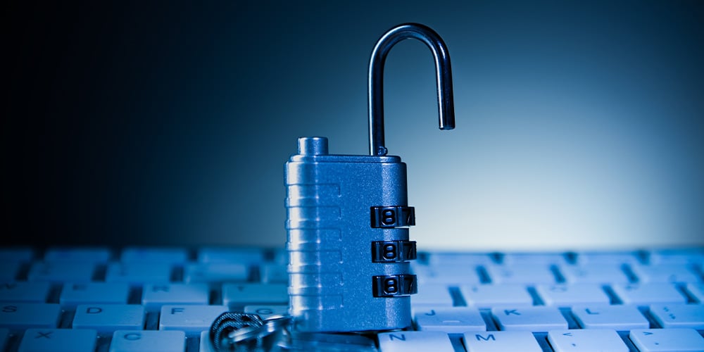 Open combination padlock resting on a computer keyboard.