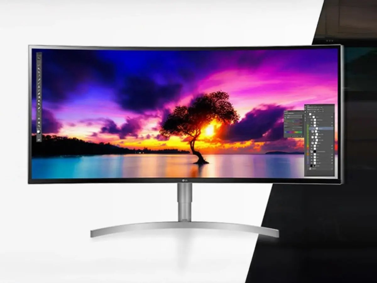 Curved monitor displaying vibrant sunset over a lake with a silhouette of a tree. Bright colors and Photoshop interface enhance creativity.