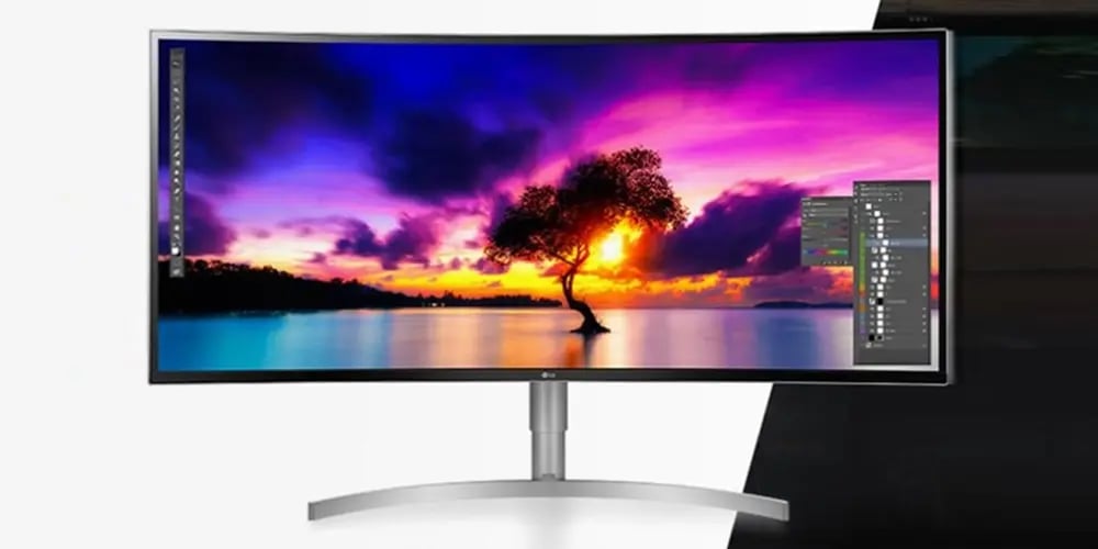 Curved monitor displaying vibrant sunset over a lake with a silhouette of a tree. Bright colors and Photoshop interface enhance creativity.
