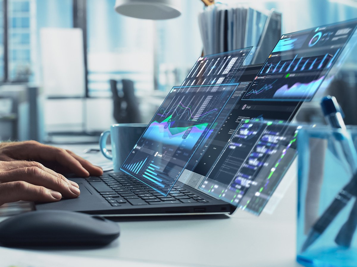 Transparent analytics dashboards floating above a laptop displaying charts, metrics, and trend lines.