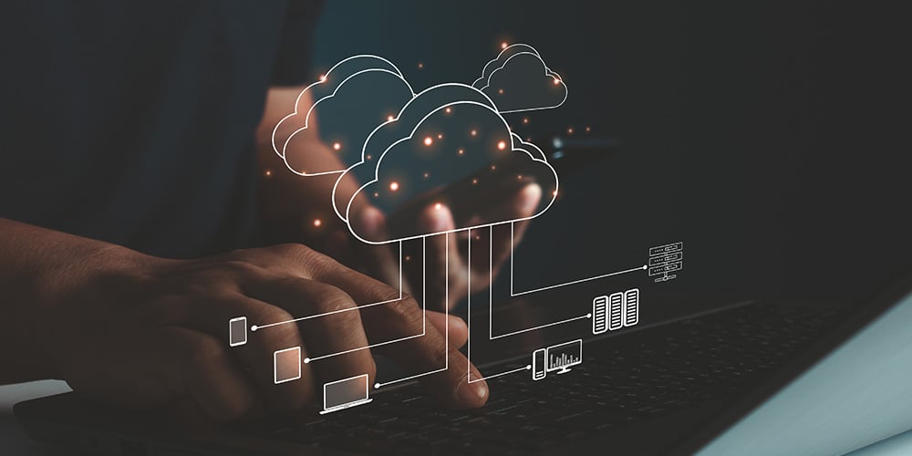 Hands using a laptop with illustrated cloud icons and connected devices to represent cloud data processing.