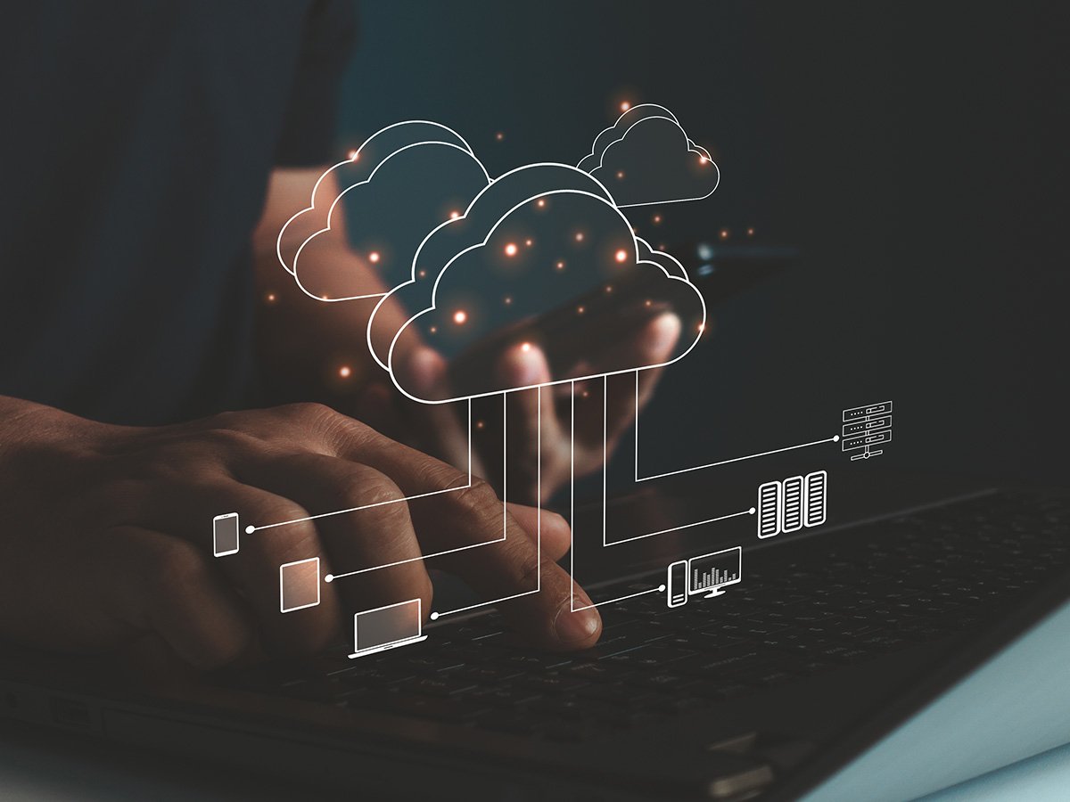 Hands using a laptop with illustrated cloud icons and connected devices to represent cloud data processing.