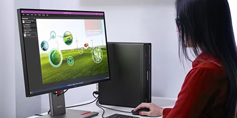 Person using a desktop computer with a monitor showing renewable energy graphics.