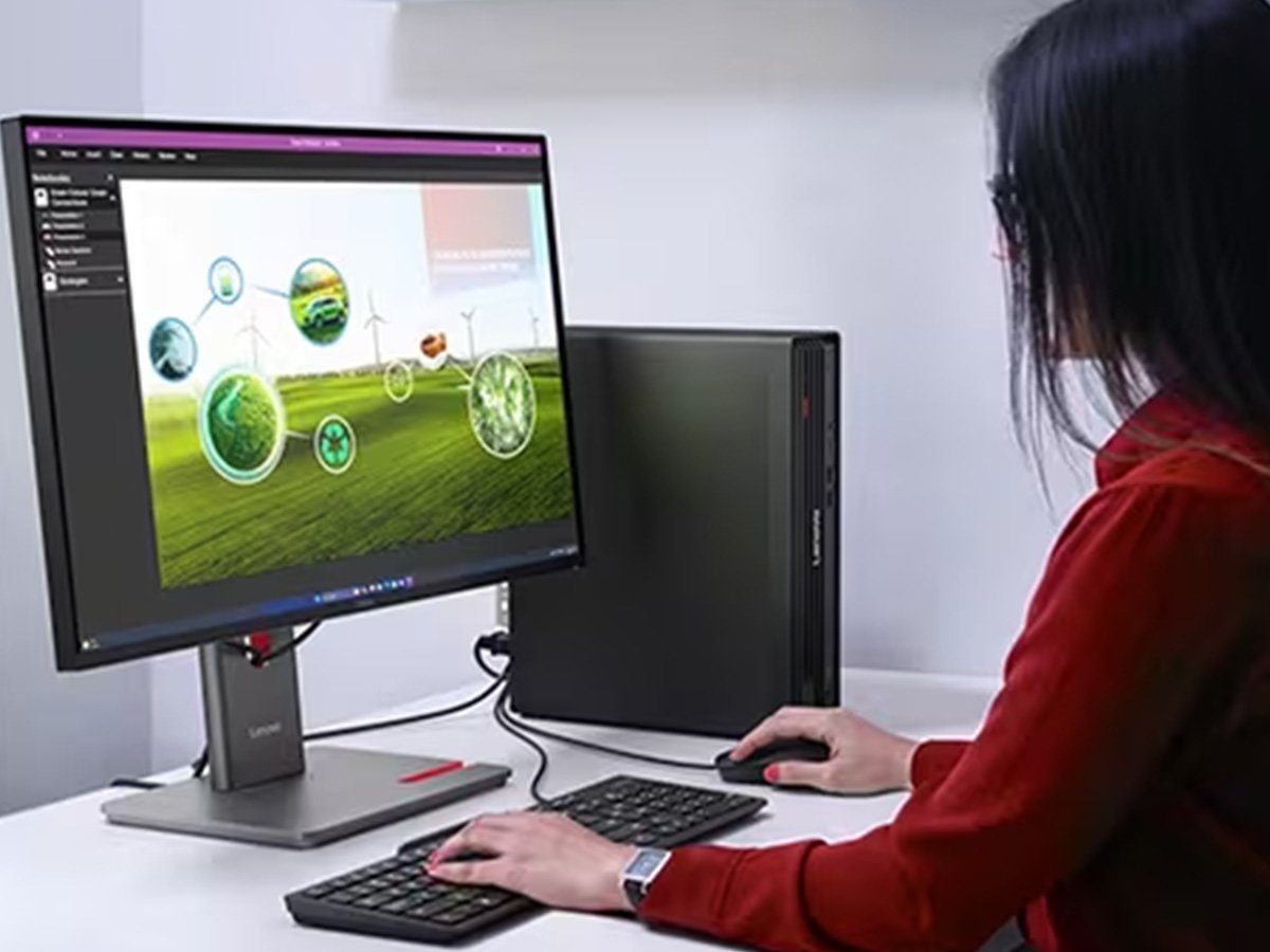 Person using a desktop computer with a monitor showing renewable energy graphics.