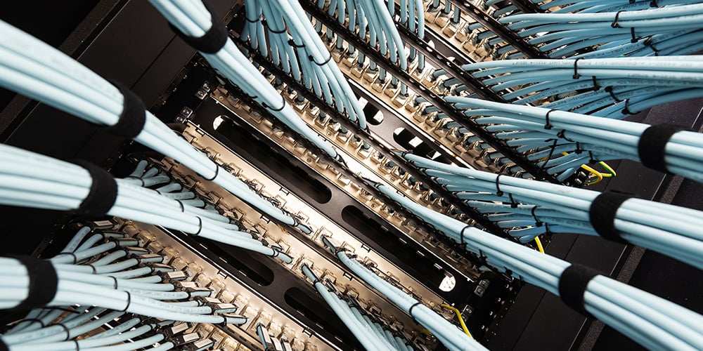 Close‑up of network cables connected to servers inside a data centre rack.