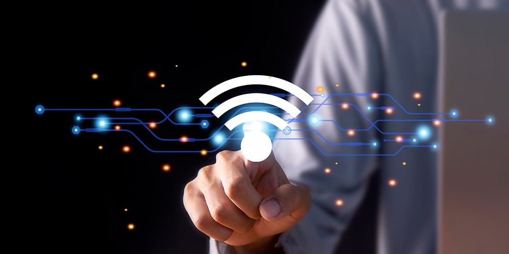 Hand touching a glowing Wi‑Fi icon over digital circuit lines.