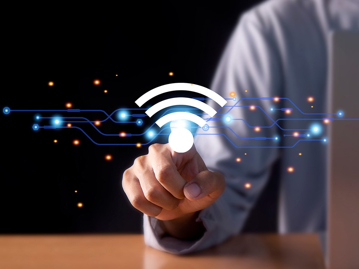Hand touching a glowing Wi‑Fi icon over digital circuit lines