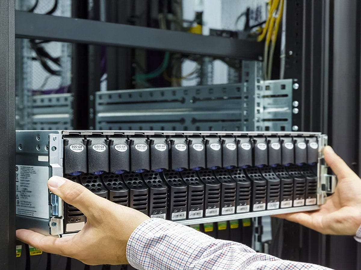 Hands installing a server component into a rack in a data center.