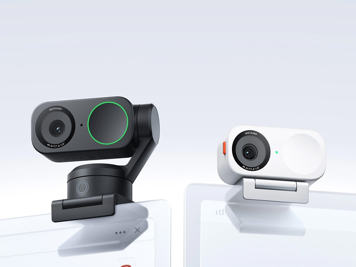 Two clip-on webcams, one black and one white, attached to screens.