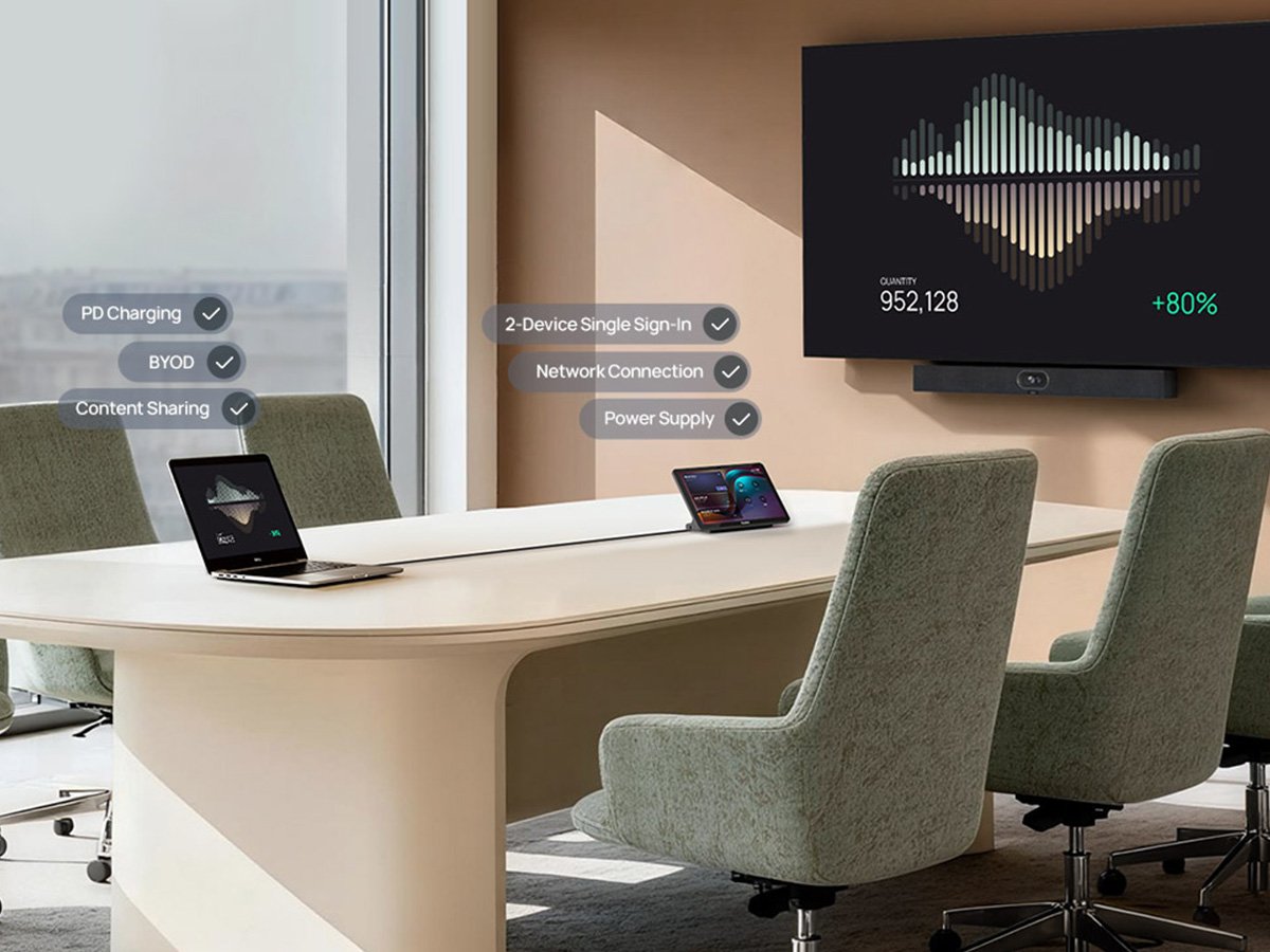 Modern meeting room with a large screen and laptops on the table.