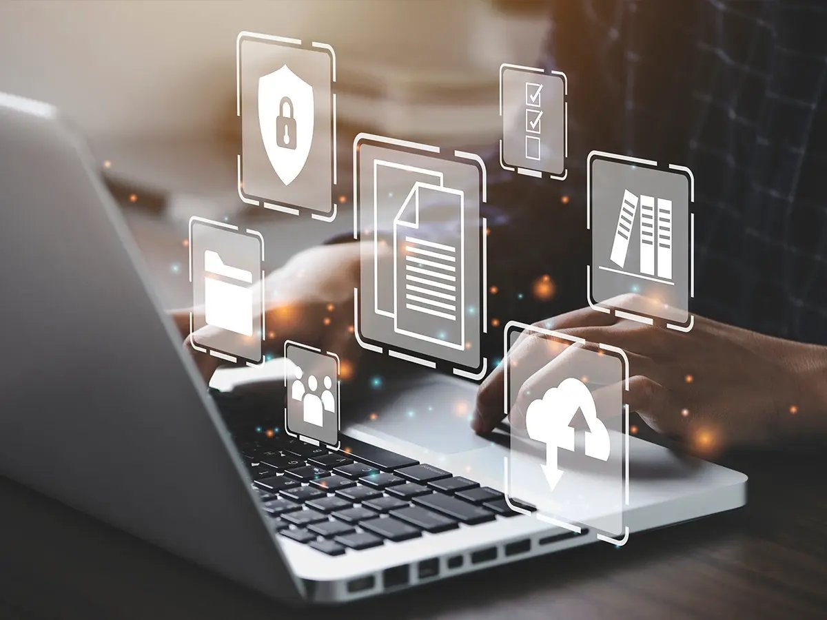 Hands typing on a laptop with floating digital icons, symbolizing automated processes for secure data erasure and management.