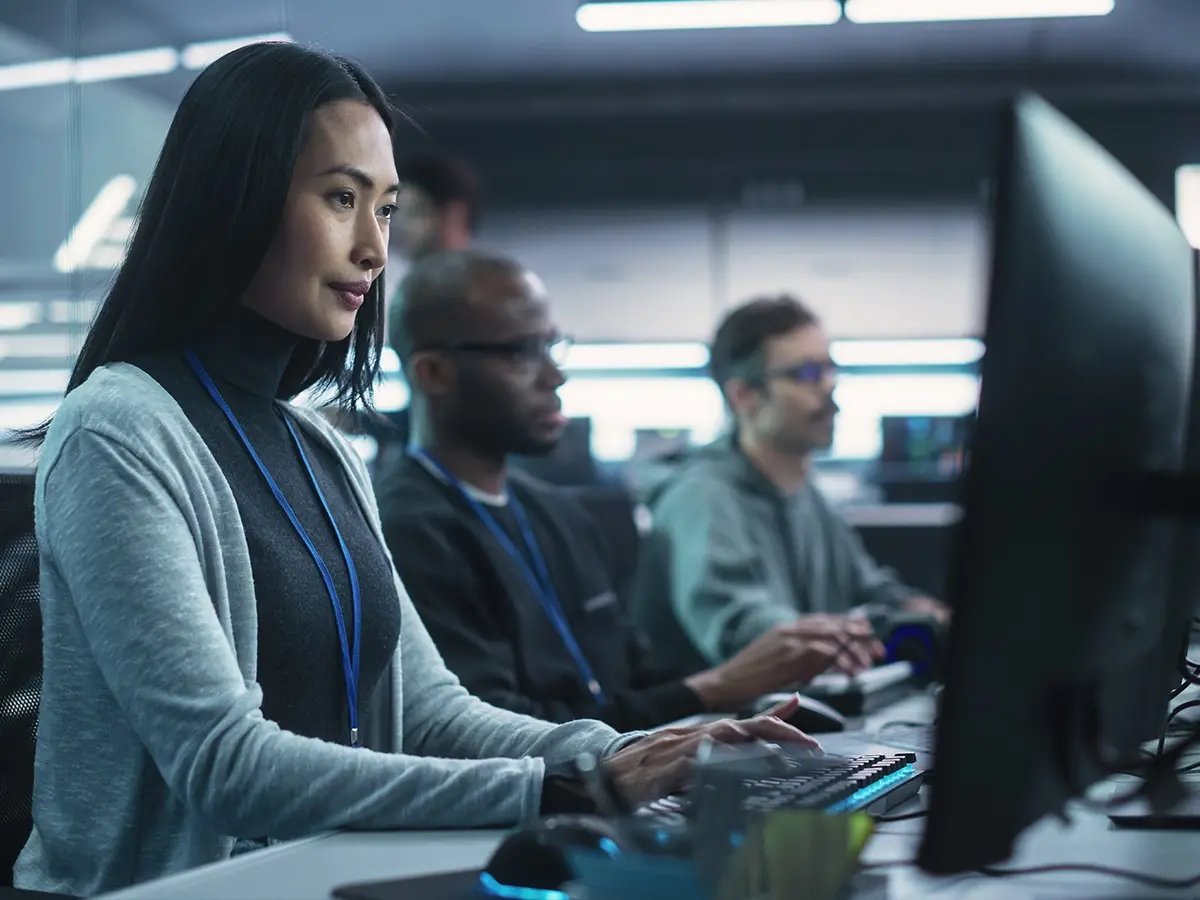 People working on desktop computers in a modern office environment, representing data erasure delivered as a managed service.