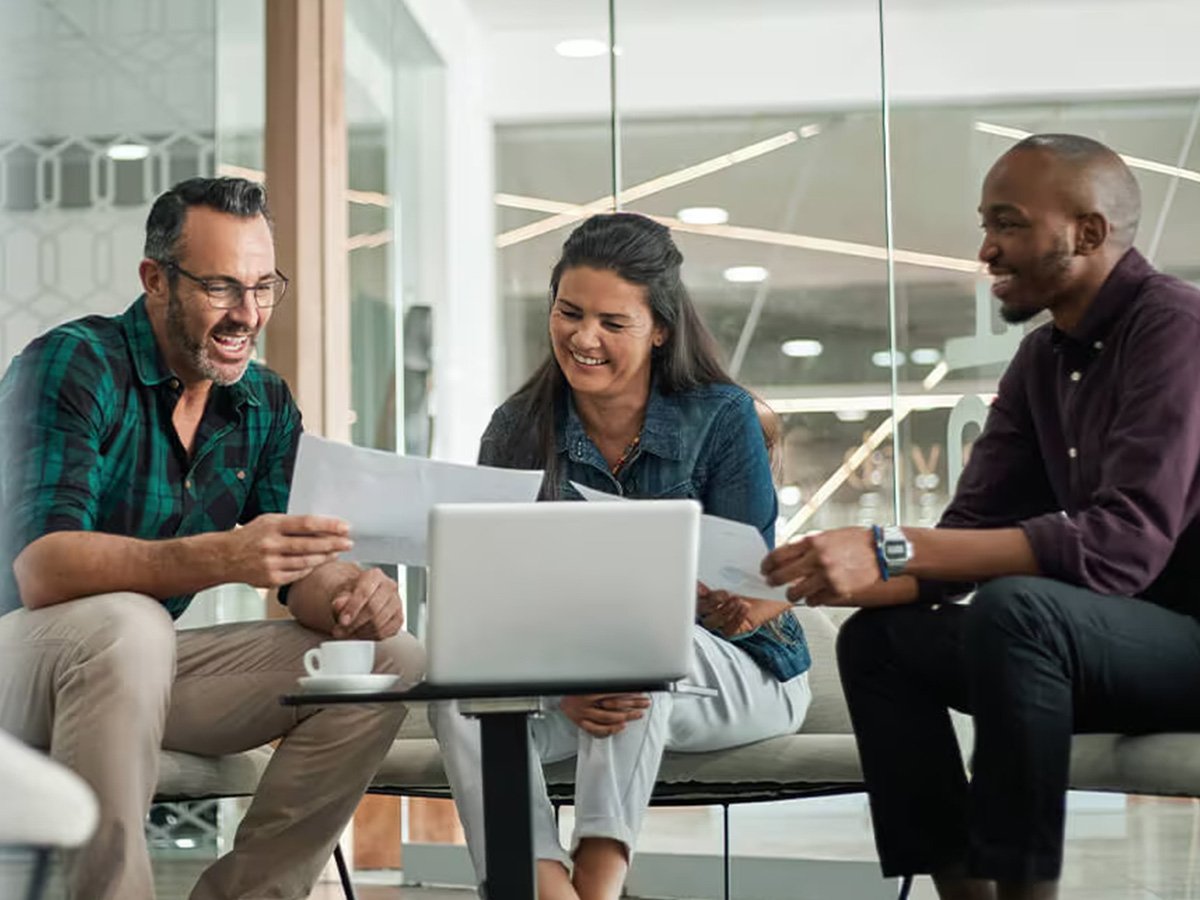 3 colleagues working together in front of a laptop and looking at documents