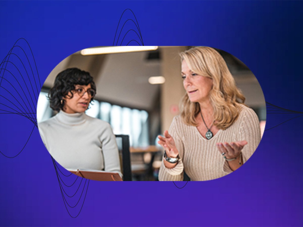 Two colleagues discussing work while reviewing notes on a tablet in an office