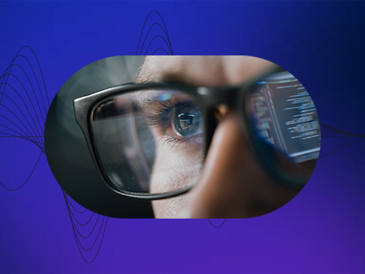 Close-up of an eye behind glasses with code reflected on the lenses