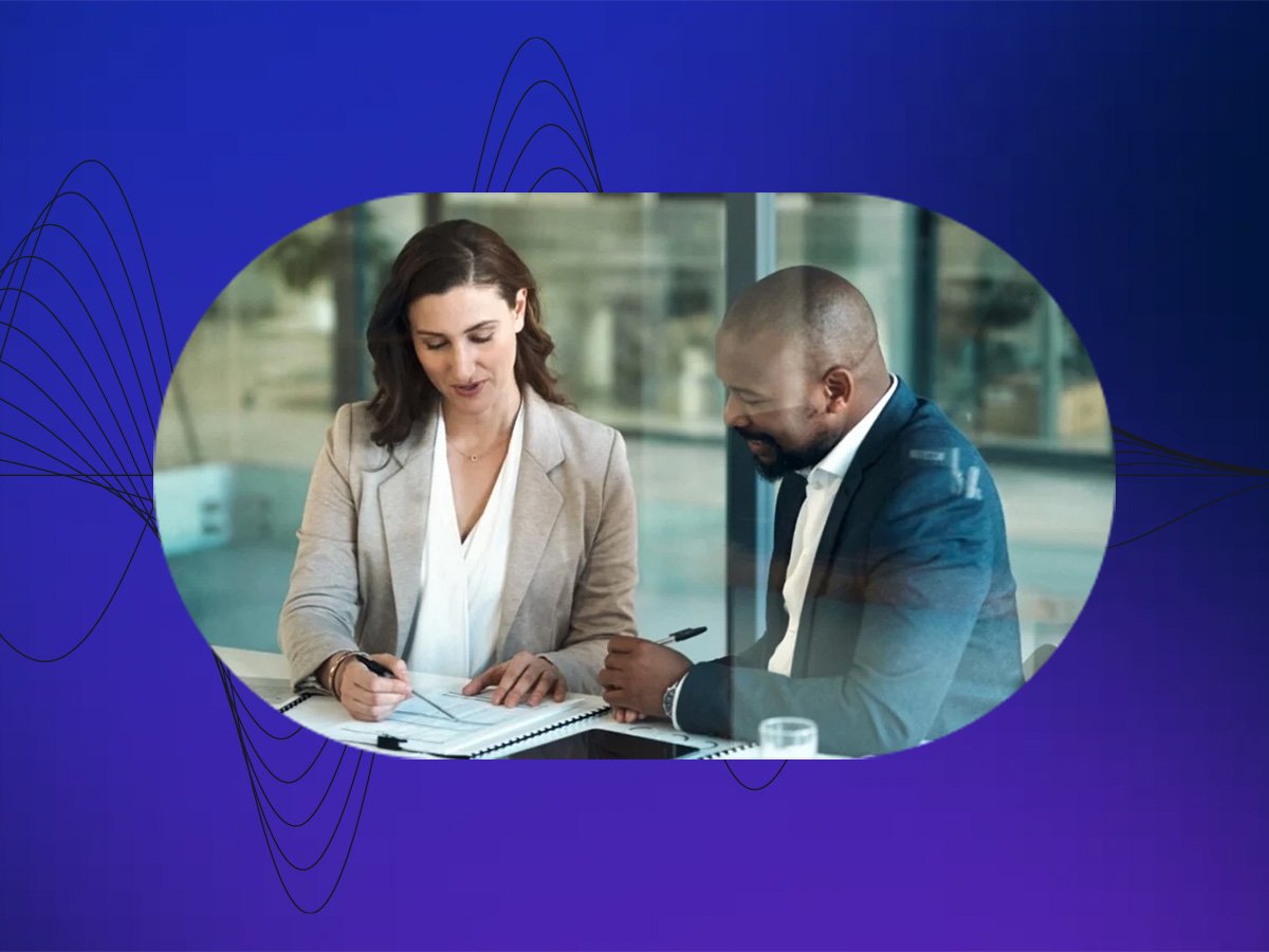 Two professionals reviewing documents together at a table in a modern office