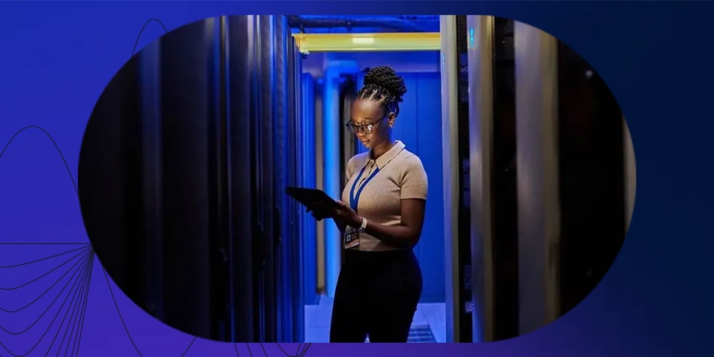 Technician using a tablet between server racks in a data centre