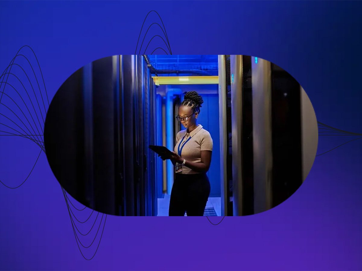Technician using a tablet between server racks in a data centre