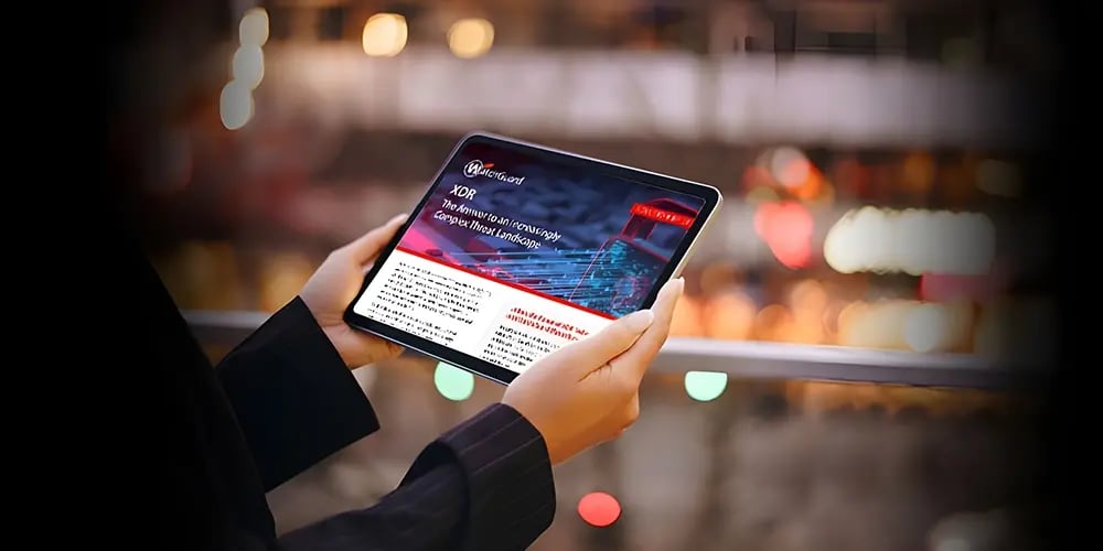 A person holding a tablet displaying a presentation on XR technology, with text and graphs visible. The background shows a blurred view of lights and colors, suggesting an urban setting.