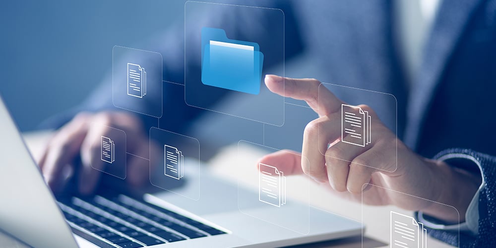 Close-up of a person using a laptop and interacting with virtual desktop folders and document icons on a transparent interface.